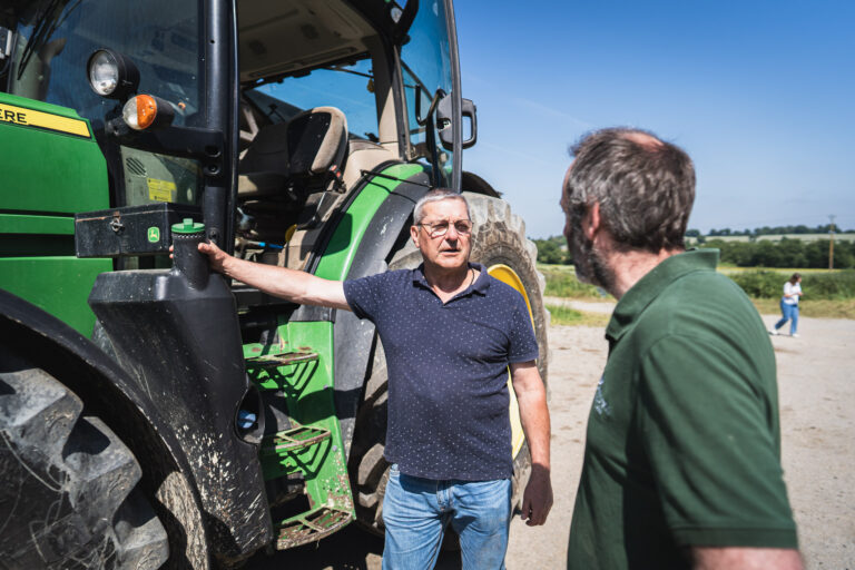 Edouard discute avec un agriculteur près de son tracteur